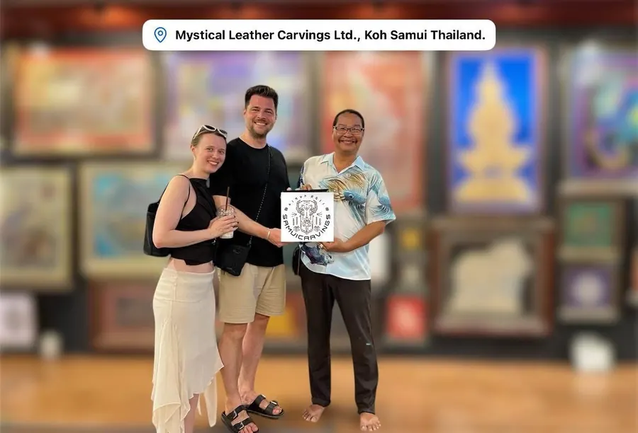 The artist with two guests, holding a framed leather carving in his gallery