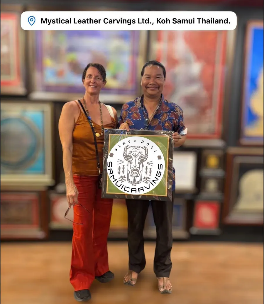 The artist with a guest holding a framed leather carving in his gallery