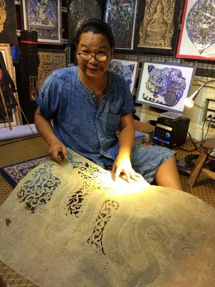 Mr. Choawalit Champathip cutting a large hide that a lamp lights from below