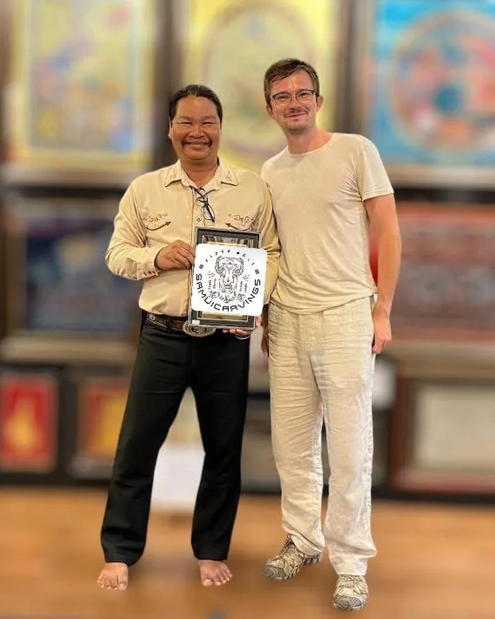 Mr. Choawalit and a guest in the gallery, holding a small framed Samui Carvings print