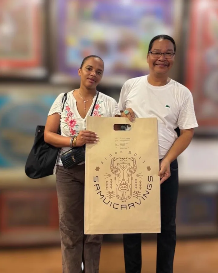 Mr. Choawalit and a guest holding a Samui Carvings bag